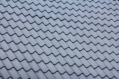 Dalgalı desenli mavi-gri metal çatı kiremitlerinin detaylı dokusu ışık ve gölge efektleri yaratır