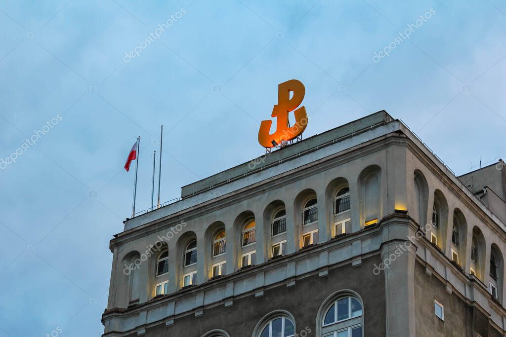 Historic Building with Golden Letter B Logo and Flag Atop Displaying Classic Architectural Style Against Blue Sky
