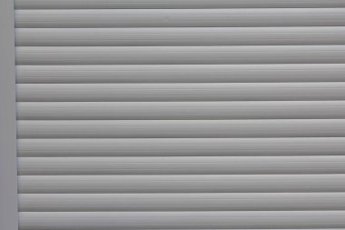 Gri metal pencere panjuru ya da yatay kirişli garaj kapısı paralel çizgiler ve gölgeler oluşturuyor.