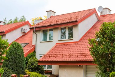 Terracotta kırmızı kiremit çatılı modern evler ve banliyö yerleşim alanındaki küçük bahçelerin yer aldığı beyaz cepheli evler.