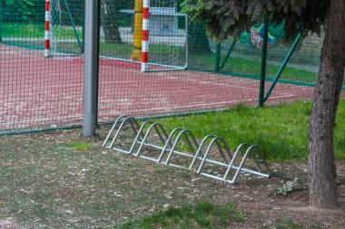 Bisiklet Depolama Rafı Yeşil Çit ve Güvenlik Ekipmanlarıyla Spor Alanının yanında