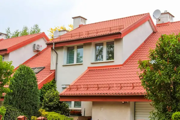 Terracotta kırmızı kiremit çatılı modern evler ve banliyö yerleşim alanındaki küçük bahçelerin yer aldığı beyaz cepheli evler.