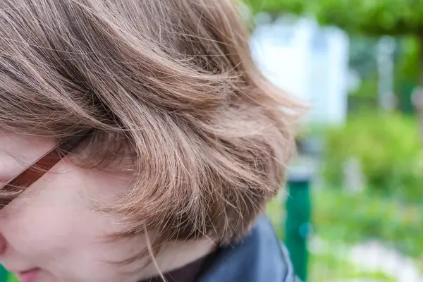 Bulanık Yeşil Bahçe Arkaplanına Karşı Doğal Işıklı Kadın Dalgalı Saçının Yakın Çekimi