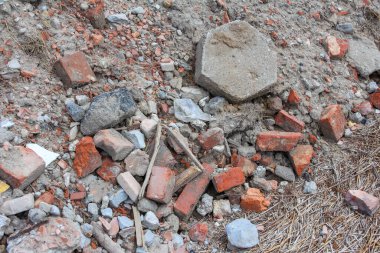 Parçalanmış kırmızı tuğla parçaları ve beton döküntüleri yıkım sonrası toprak zeminde yatıyor.