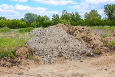 İnşaat alanı kazılmış toprak tepecikleri ve dağınık beton molozlarla yeşil kırsal alan