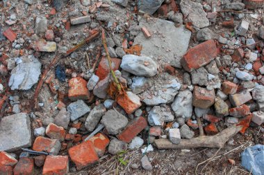 Kırmızı tuğla parçaları ve yere saçılmış beton parçaları içeren karışık inşaat enkazlarının yakın görüntüsü