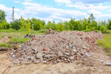 Büyük bir beton yığını ve inşaat enkazı bulutlu gökyüzünün altındaki boş kırsal inşaat sahasına saçılmış.