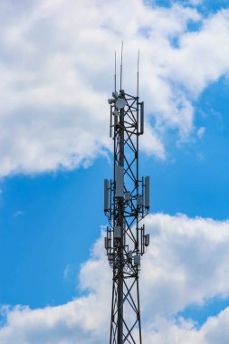 Karmaşık anten sistemine sahip telekomünikasyon direği dramatik mavi ve beyaz bulutlu gökyüzüne karşı siluetlendi