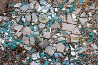 Parçalanmış yeşil ve beyaz seramik karoların mozaik benzeri deseni zemini kaplayarak, kırık kalıntıların dokulu bir arka planını oluşturur.,