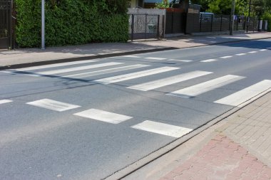 Asfalt yol yüzeyinde beyaz çizgili zebra desenli şehir yaya geçidi.