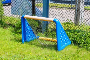 Yeşil çimlerin üzerine kurulmuş mavi futbol eğitim ekipmanları eğlence amaçlı spor alanında tel örgüler var.