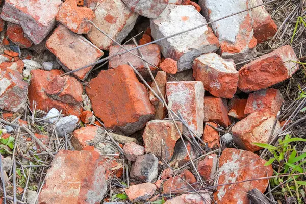 Yıpranmış kırmızı kil tuğlaların yakın çekim yığını düzensiz olarak doku ve yaşlanmayı gösteriyor