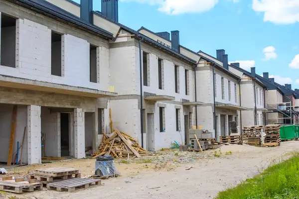 Mavi gökyüzü ve yeşil ağaçlarla inşa edilmiş modern kasaba evleri.