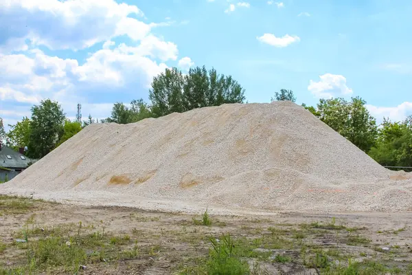 Büyük kum yığını ya da inşaat malzemesi bulutlu mavi gökyüzüne karşı