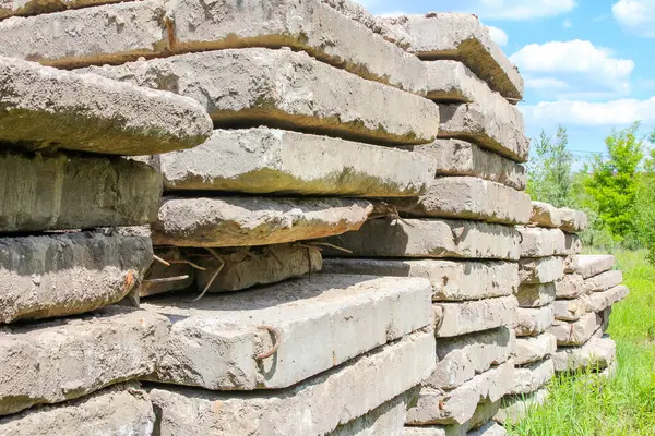 Yıpranmış kireç taşı blokları açık alanda yeşil yeşillik arka planına karşı dikey kulede dizilmiş.