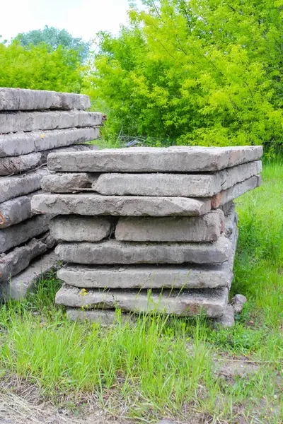 Bahçedeki yemyeşil bitki örtüsüyle çevrili kireç taşı blokları olan taş istinat duvarı.