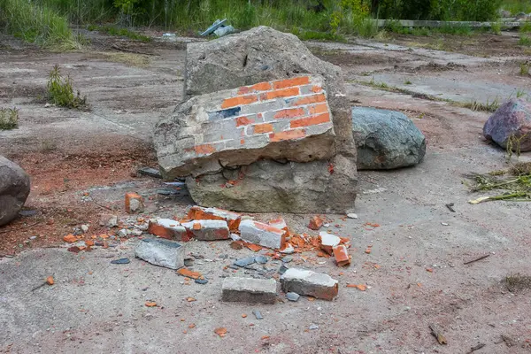 Büyük, kısmen tahrip edilmiş beton bir yapı, dağınık tuğlalar ve molozların arasında duruyor. Bu da kentsel bozulmayı veya yıkımı gösteriyor.,