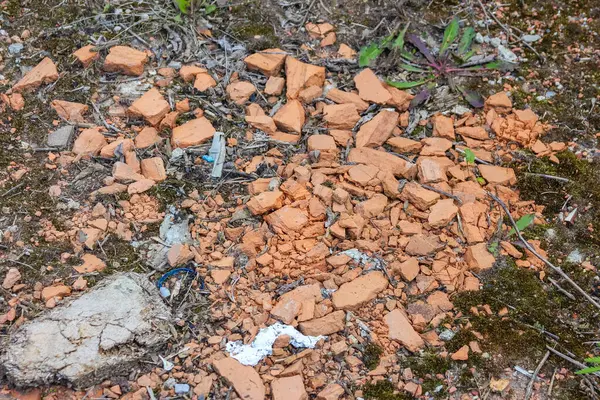 Kırmızımsı kahverengi tuğla parçalarının yakın plan görüntüsü ve toz zemini kaplayarak yıkımın dokulu bir arka planını oluşturur.,
