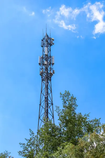 Uzun metal telekomünikasyon kulesi anten yapısı beyaz bulutlu açık mavi gökyüzüne karşı