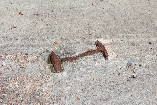 Beton yüzeye gömülmüş paslı metal çivi ya da çivi aşınma ve yıpranma etkilerini gösteriyor.