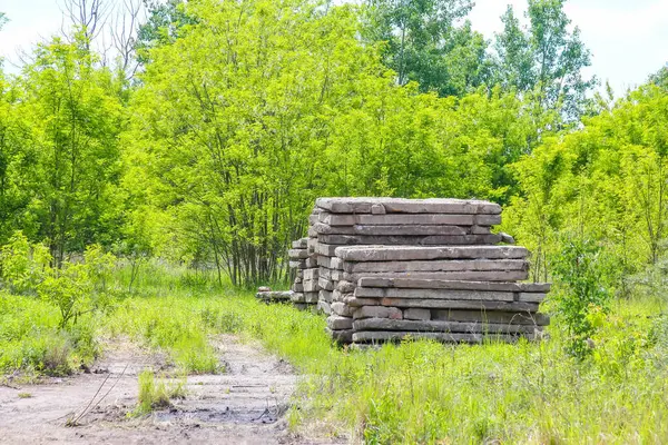 Yığılmış beton levhalar inşaat alanındaki yemyeşil orman zeminine karşı geometrik kule oluşumu yaratır