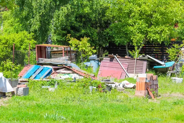 Renkli çocuk parkı ekipmanları ve banliyö evlerinin yakınındaki yeşil çimlere saçılmış çocuk oyuncakları olan bir yerleşim yeri.