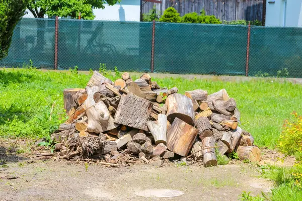Düzgünce istiflenmiş yakacak odun yığını ya da yeşil çimenlerin üzerinde kesilmiş kütükler, kış için hazırlık, sürdürülebilir yaşam ya da kırsal bir açık hava ortamı öneriyor.,
