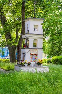 Huzurlu park ortamında yemyeşil ağaçlarla çevrili küçük beyaz şapel ya da türbe yapısı