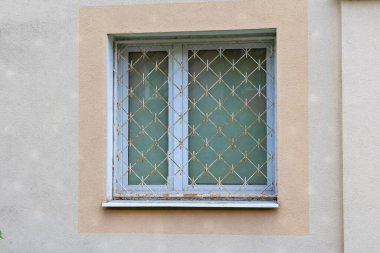 Bej dış bina duvarında dekoratif cam desenli beyaz pencere çerçevesi