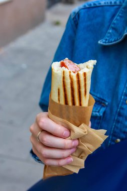 Mavi ceketli biri, elinde geleneksel ballı waffle külahı ile sokak yemeklerine damlıyor.
