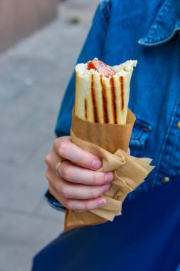 Elleriniz yakın plan altın renkli waffle külahını tutarken açık havada serpiştiriliyor. Geleneksel sokak yemekleri hazırlanıyor.