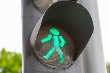 Trafik kontrol sisteminde bulanık şehir arka planına karşı yeşil yaya geçidi sinyal lambası yürüyen figürü