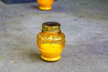 Altın kehribar cam kavanoz bulanık arka planlı gri beton yüzeyde tek başına oturuyor.