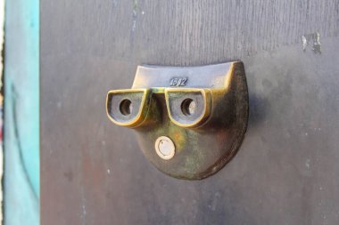 Eskimiş, eskimiş, kahverengi ahşap bir kapı. Eski metal bir gözetleme deliği görüntüleyicisi var. Yaş ve tarih belirtileri gösteriyor..