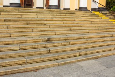 Geniş, açık bir taş merdiven, bir çok basamakla, parlak bir gökyüzünün altındaki bir binaya açılıyor..