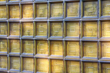 Şeffaf cam blok bir duvar yakın çekim ızgara deseni ile, sıcak, güneşli tonlar ile soyut bir arkaplan dokusu oluşturur.