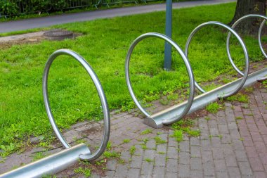 Bir sıra modern, minimalist bisiklet park alanında yeşil çimenler ve parlak bir gökyüzünün altında asfalt yollar var..