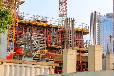 Modern bir yapı inşa etmenin erken aşamalarını gösteren yapı iskelesi ve beton biçimlere sahip büyük bir inşaat alanı..