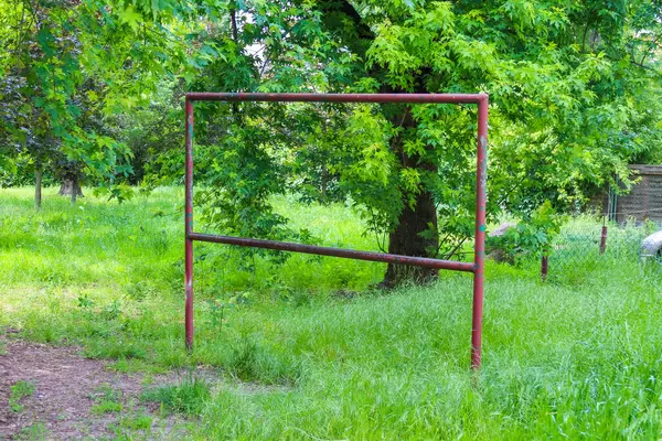 Gündüz vakti yeşil çimenlik alanda tek başına duran boş bir metal gol çerçevesi