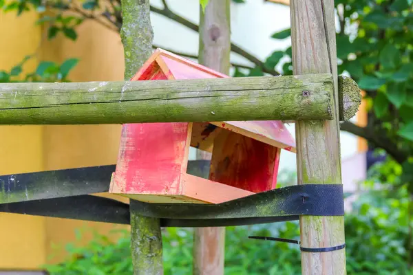 Ahşap kitaplık. Açık hava bahçe ortamında birden fazla rafa dizilmiş renkli kitaplar.