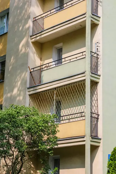 Beyaz balkon parmaklıkları ve dikdörtgen mimari tasarım elementleri olan modern bej apartman.