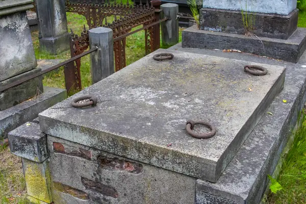 Dairesel açıklıklı taş mezar taşı tabelaları beton mezarlık zemininde düz duruyor.