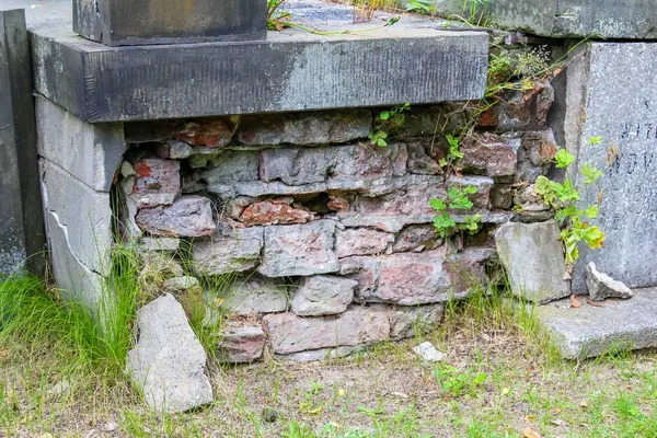 Yığılmış kayaları olan eski taş temel yeşil bitki örtüsü arasında kırsal bahçe duvarı yapısı oluşturuyor.