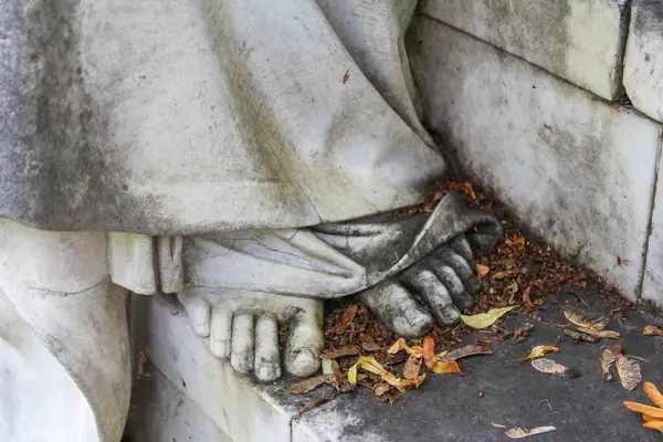 Üzüntü ve anma anıtında çiçek tutan sarkık taş heykel elleri.