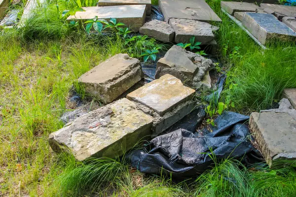 Mezarlık bakım ekipmanları ve doğal çürüme ile çevrili yosun büyümesi ile yıpranmış taş mezar