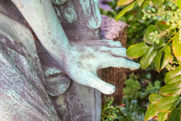 Huzurlu bahçe ortamında yeşil sarmaşık aşırı büyümesinden ortaya çıkan antik taş oyulmuş yüz heykeli