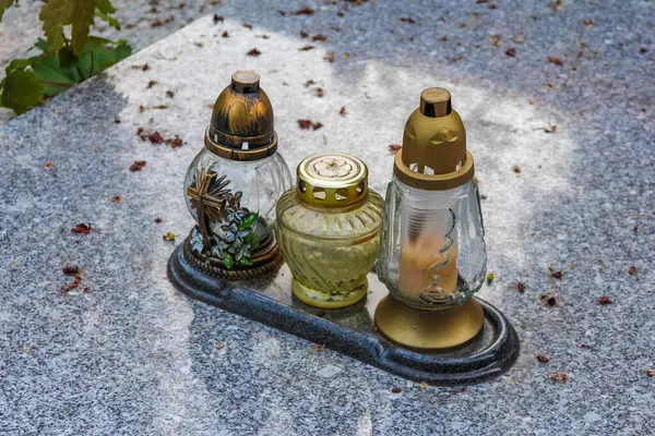 Beton mezar taşına altın alevler konulmuş geleneksel cam anıt mumlar.