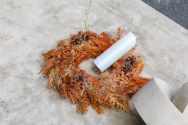 Beton bir taşın üzerine beyaz kurdeleli geleneksel kurutulmuş çiçek çelengi.