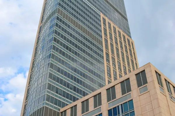 Benzersiz bir dış görünüşü olan modern gökdelen, parlak bir gökyüzüne karşı çağdaş şehir mimarisi sergiliyor..