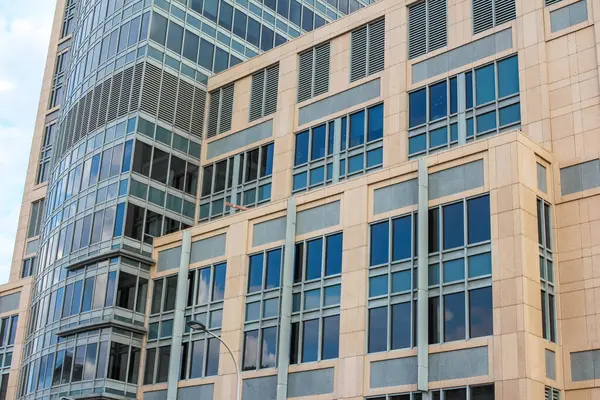 Modern bir gökdelenin karmaşık, dokulu cephesinin yakın plan görüntüsü geometrik desenlerini ve yansımalarını vurguluyor..